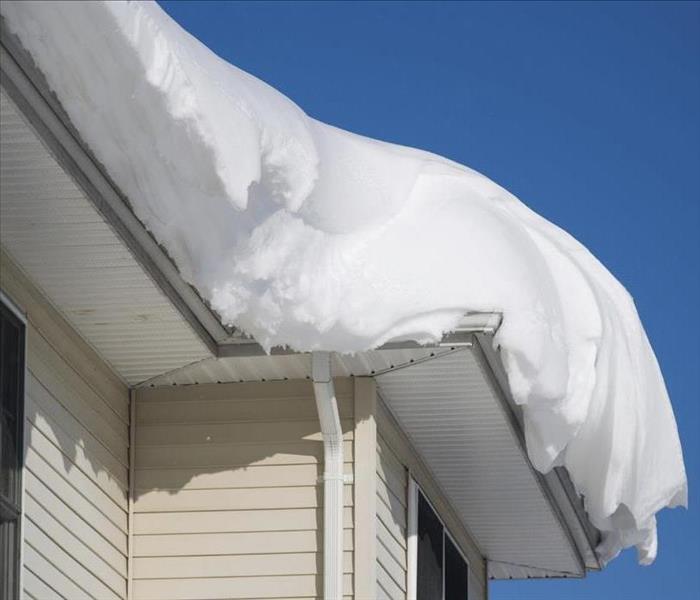 white residential home with snow covering the roof and gutters