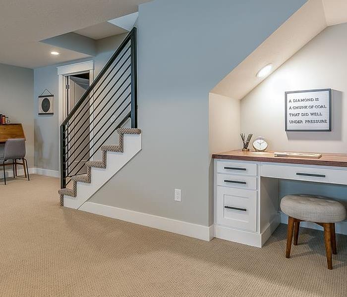 A modern basement recreation room with a home office desk underneath the stairs